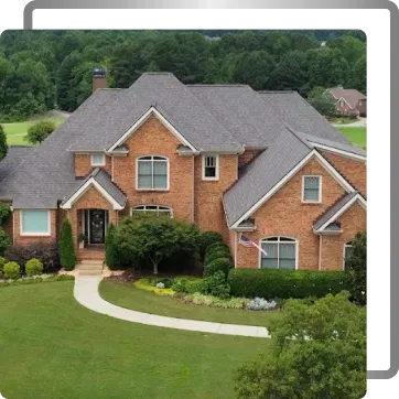 Large brick suburban house with gray roof, curved walkway, and landscaped green lawn