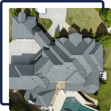 Aerial view of a gray-roofed house with a pool and green lawn.