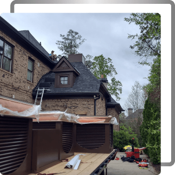 Historic brick building with dark roof under renovation, scaffolding and construction materials visible.