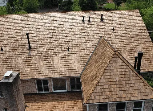 Aerial view of a shingled house roof with chimneys and skylights