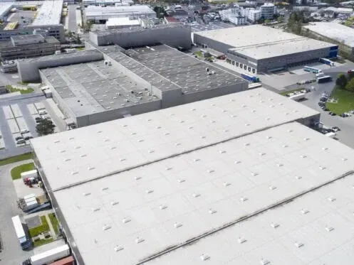 Aerial view of large industrial warehouse buildings with white roofs and surrounding parking lots