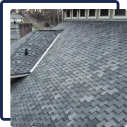 Gray shingled roof with a black vent and white trim beside another roof section