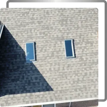 Gray shingled wall with two narrow windows, partly covered by a large shadow