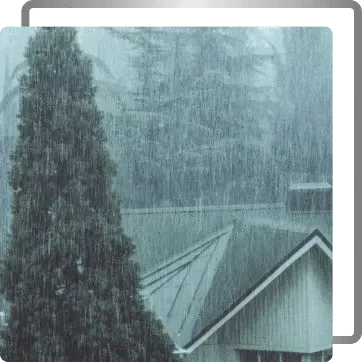 Rain pouring over rooftops and trees in a foggy residential area