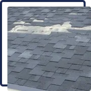 Damaged gray shingle roof with a patched white repair area