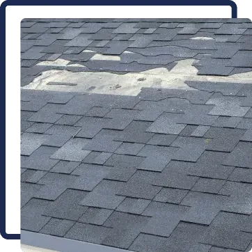 Damaged gray shingle roof with white patching material across a seam