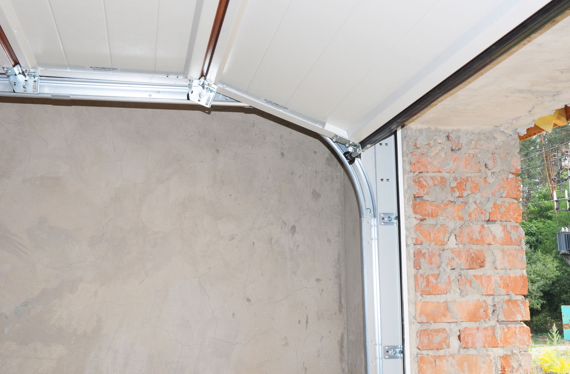 A garage door is open to a brick wall.