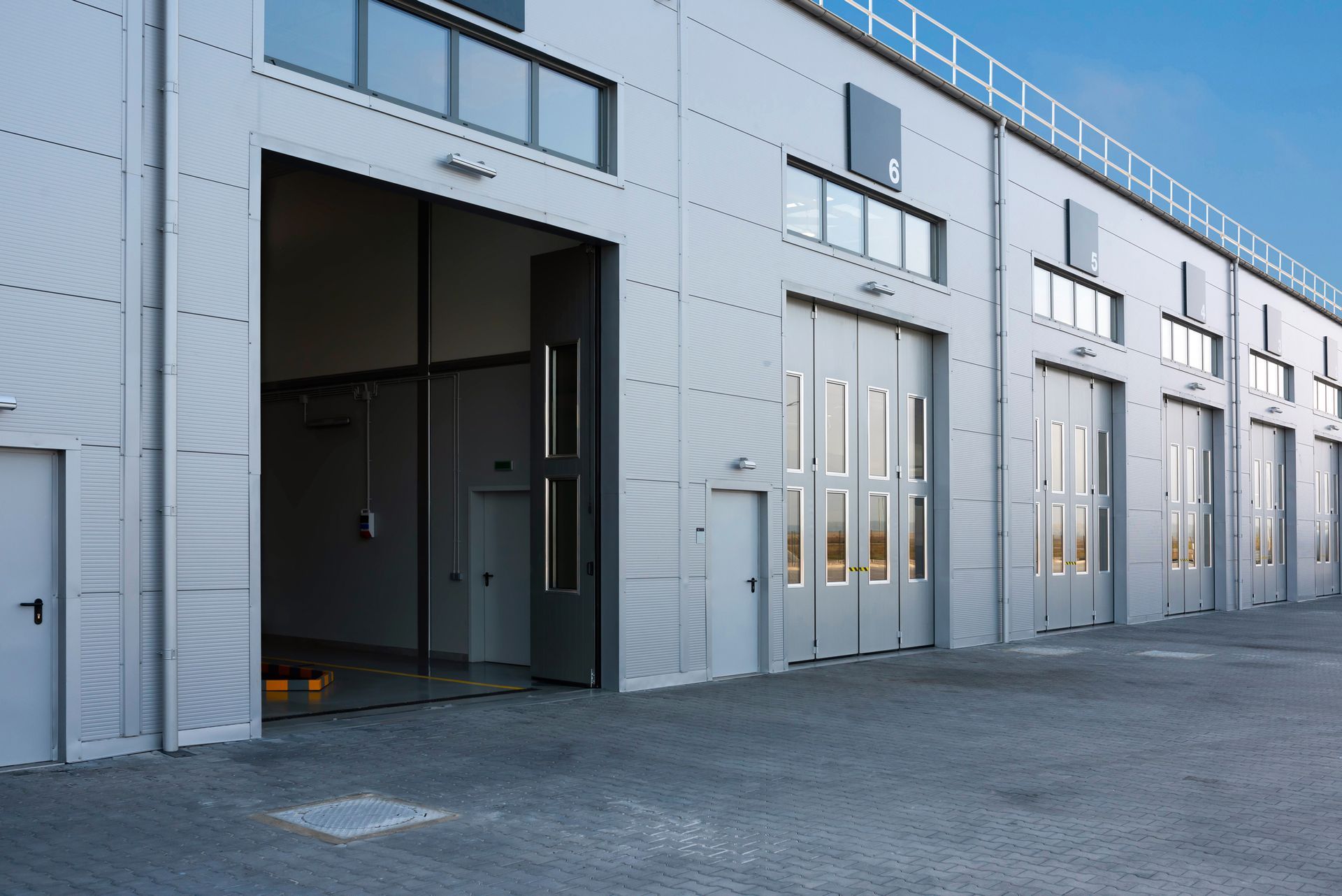 A row of warehouses with their doors open on a sunny day.