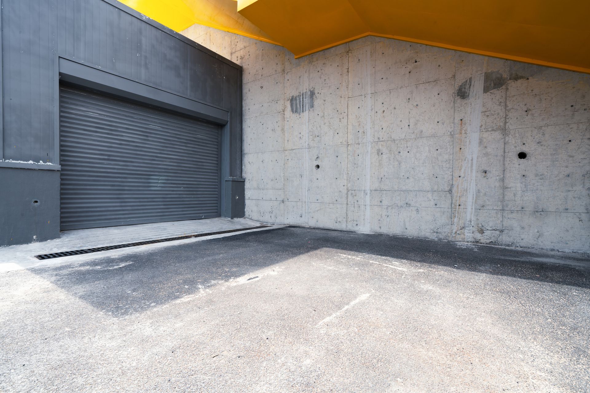 An empty parking lot in front of a building with a garage door.
