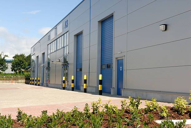 A large building with blue doors and yellow poles in front of it.