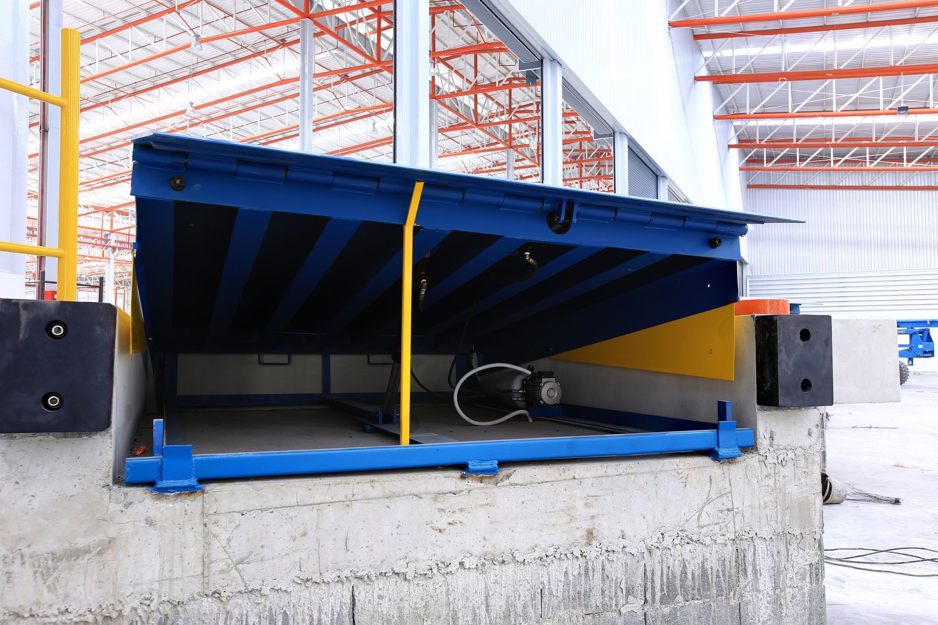 A blue and yellow dock in a warehouse with a yellow railing.