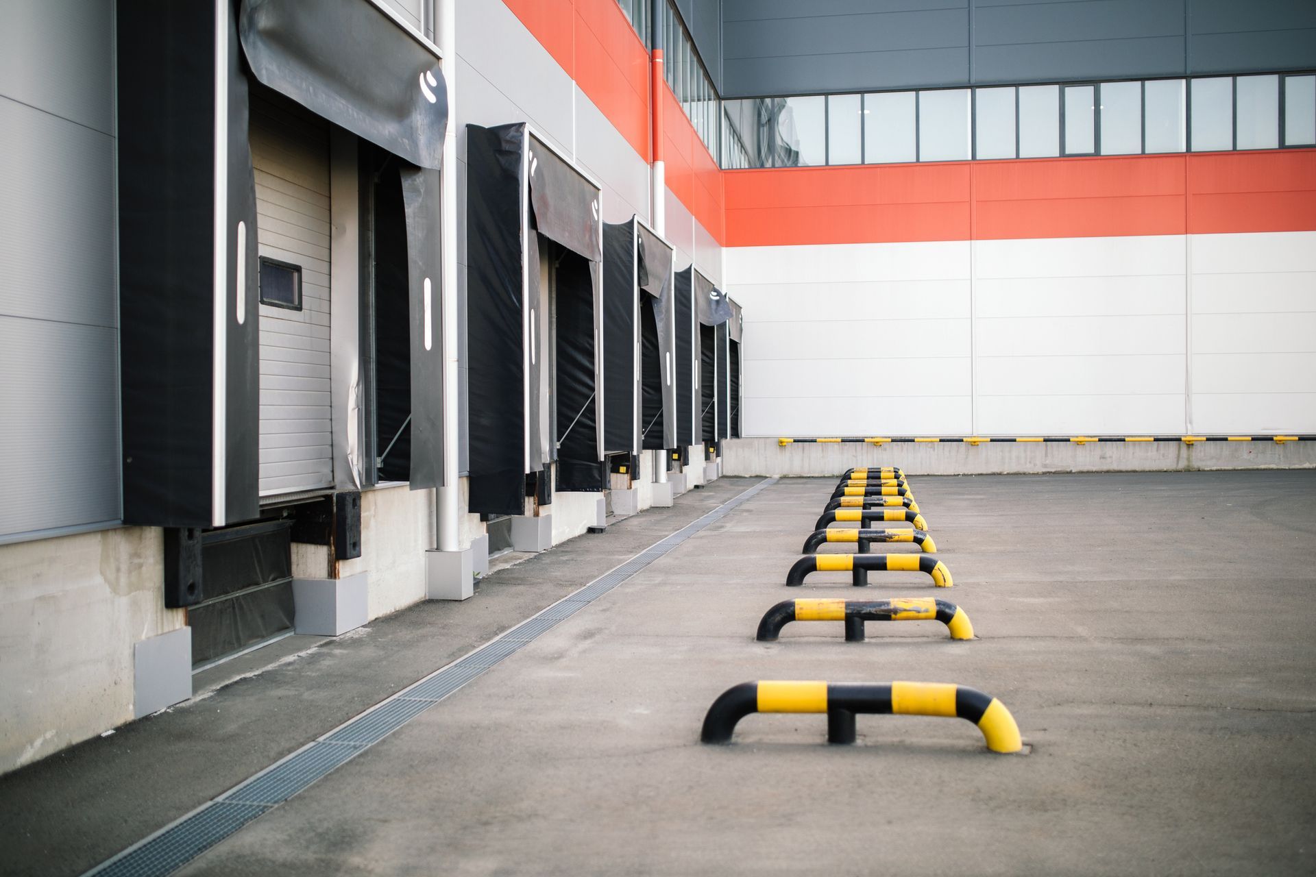 A row of loading docks in a warehouse with yellow and black barriers.