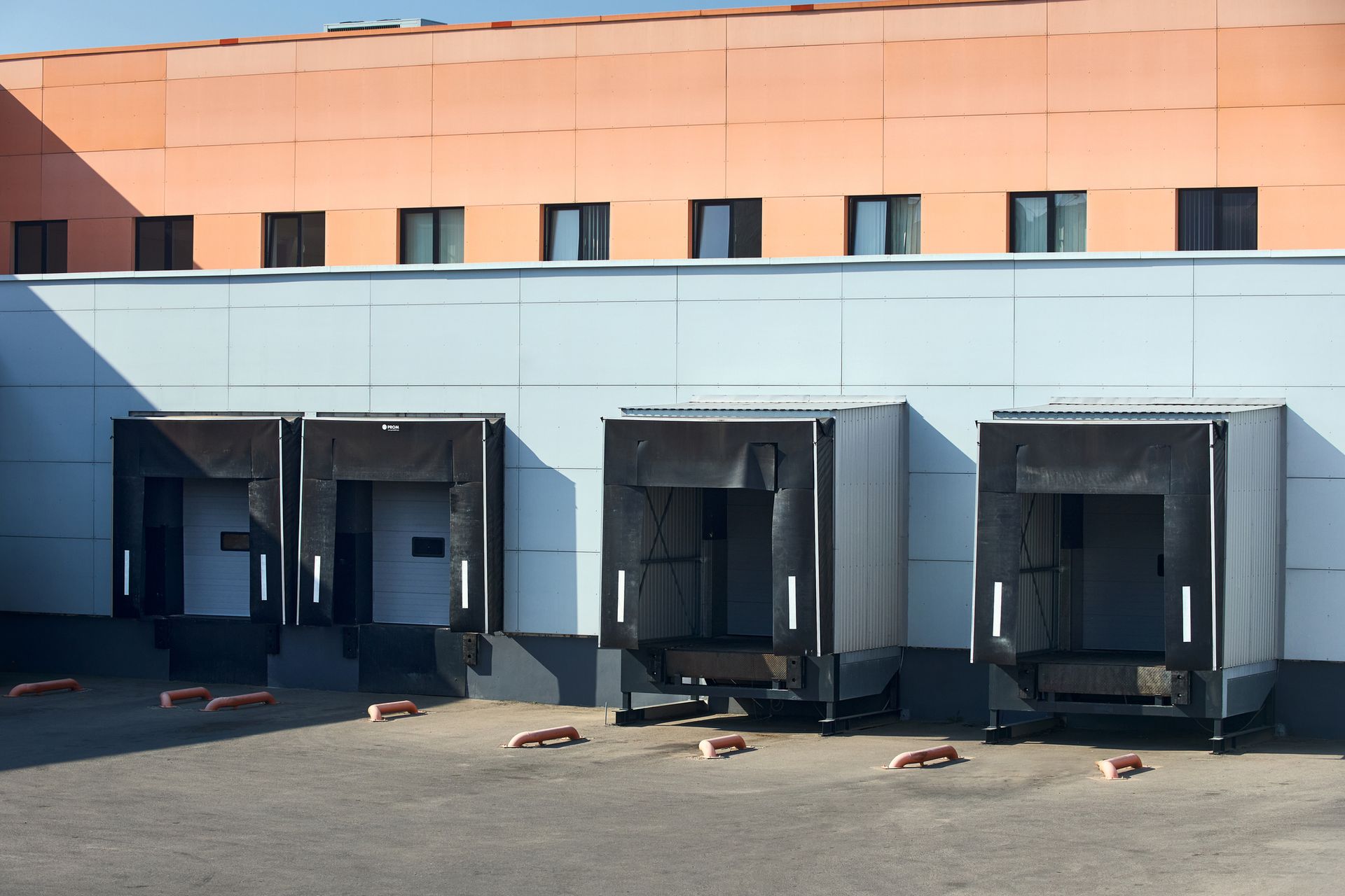 A row of trucks are docked in front of a building.