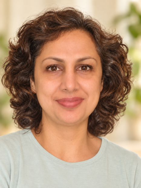 Portrait of a smiling woman with curly brown hair against a light background