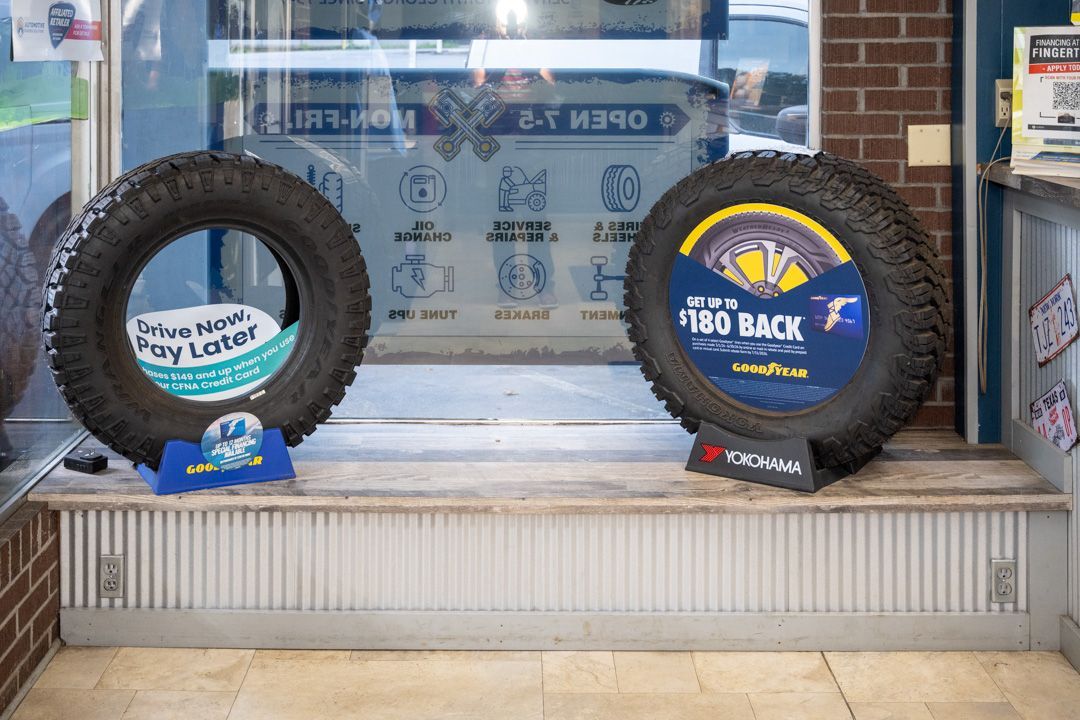 Two tires displayed on a store bench, one blue and one black, in front of a glass window.