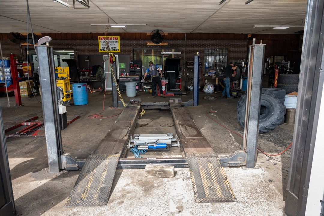 Auto repair shop interior with car lift, ramps, and tools in a cluttered garage