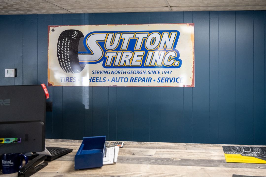 Sutton Tire Inc. sign on blue wall above a workbench in an auto repair shop
