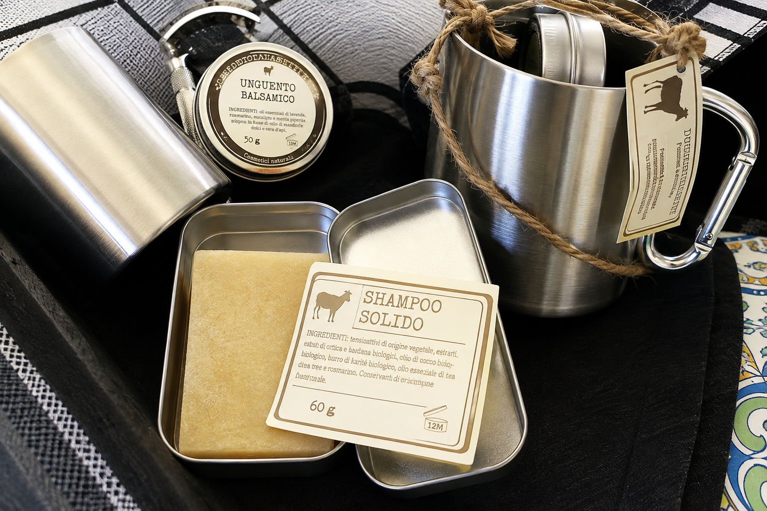 Vaschette e barattoli assortiti in argento con etichette beige, disposti su un vassoio scuro.