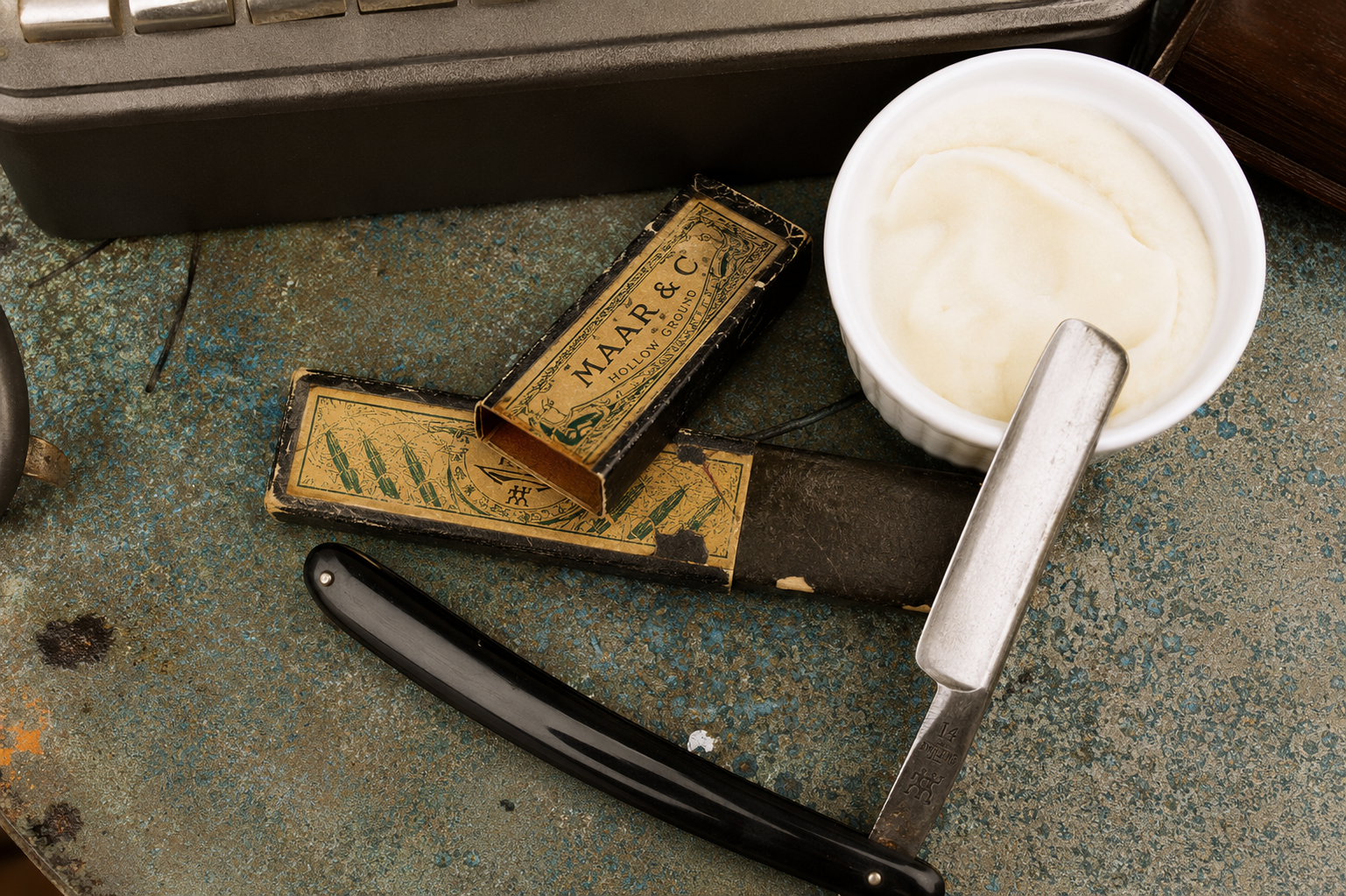 Pennello da barba, rasoio e sapone da barba su una superficie verde consumata, con astuccio in pelle.