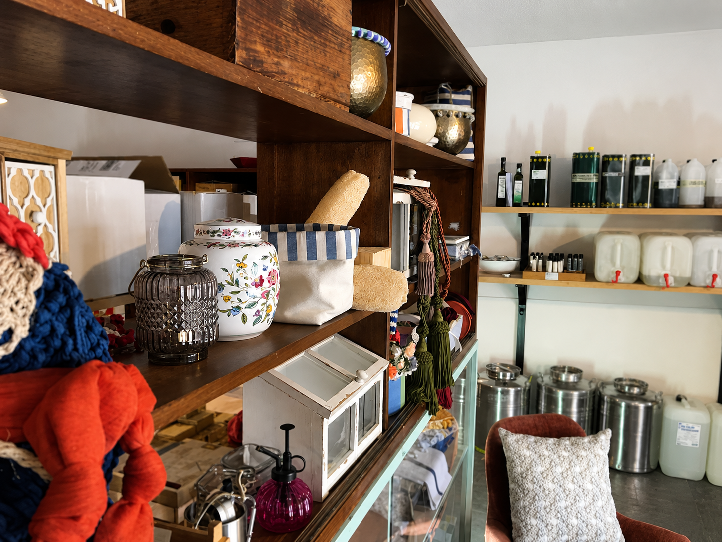 Scaffali pieni di barattoli, tazze e utensili da cucina assortiti in una dispensa luminosa o in una vetrina di un negozio.