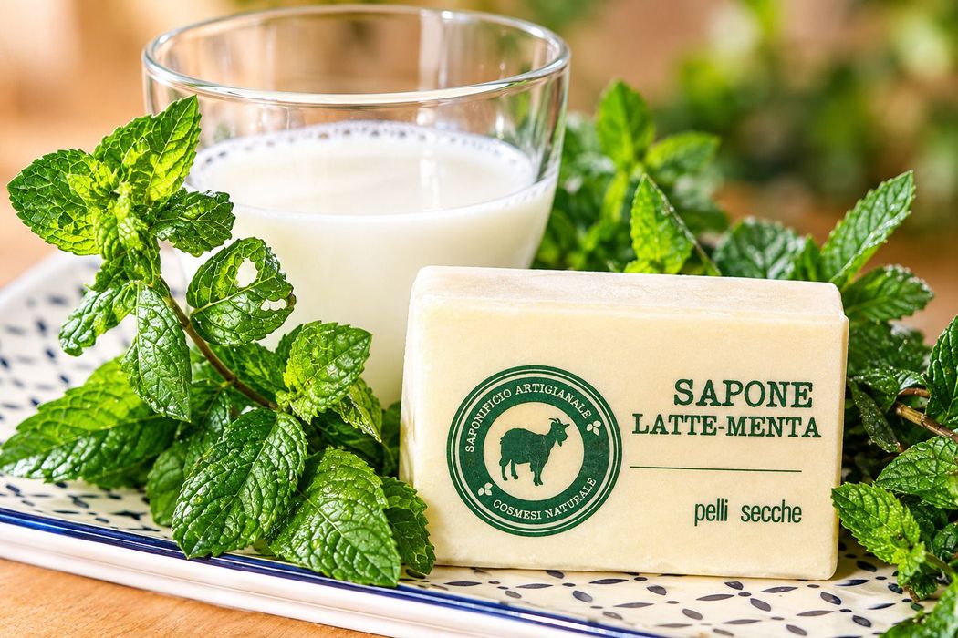 Saponetta al limone avvolta in carta, circondata da limoni giallo brillante e un cucchiaio di legno.