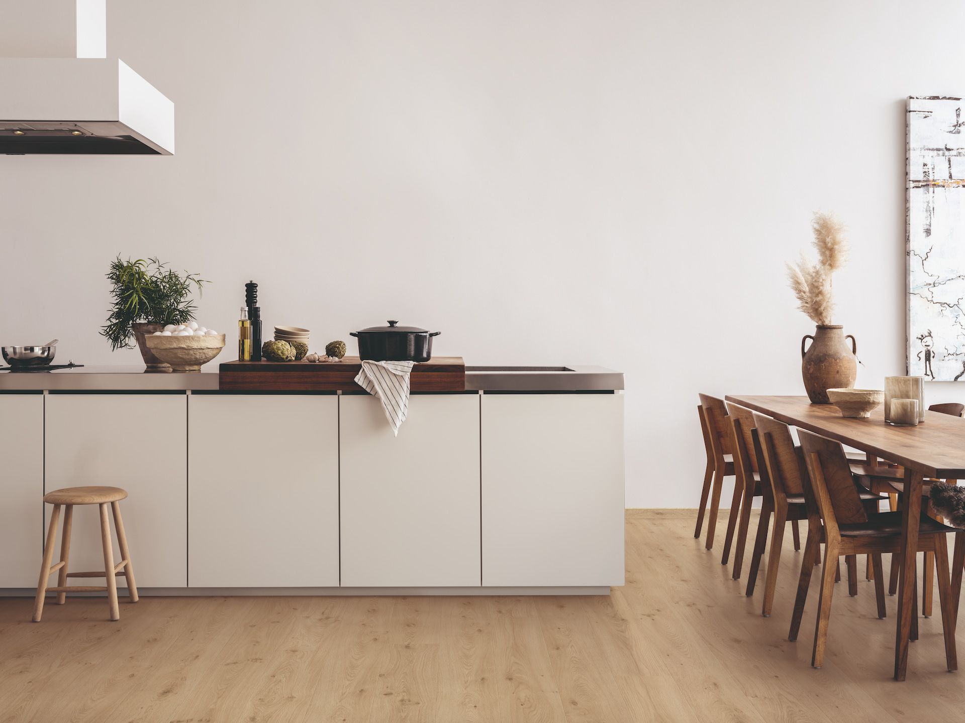 Modern Kitchen With Light Wood Floor, White Cabinets, and Wooden Dining Table — Hoppens Floorworld in Clifton Beach, QLD