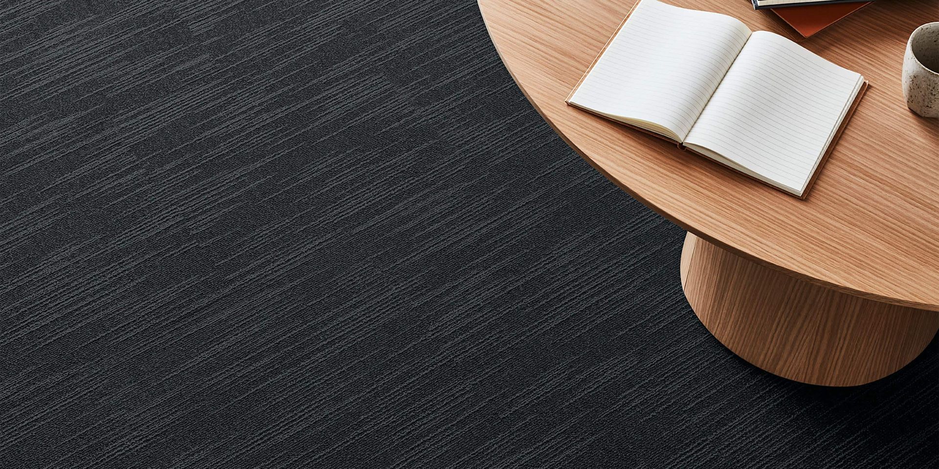 Open notebook on a wooden table beside a dark textured rug — Hoppens Floorworld in Gordonvale, QLD