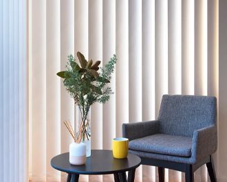 Armchair Beside a Table With a Vase of Greenery, a Cup, and Vertical Blinds — Hoppens Floorworld in Gordonvale, QLD