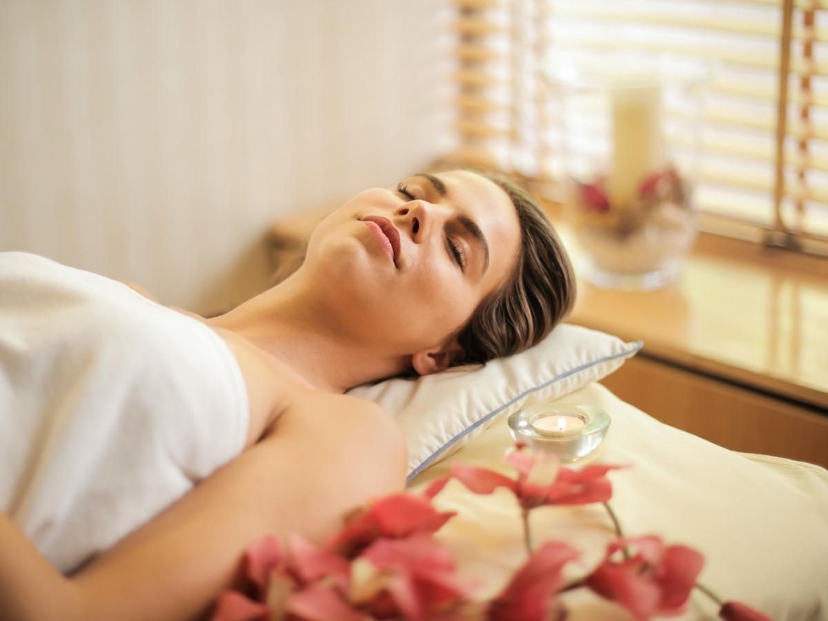 A woman is laying on a bed with her eyes closed.