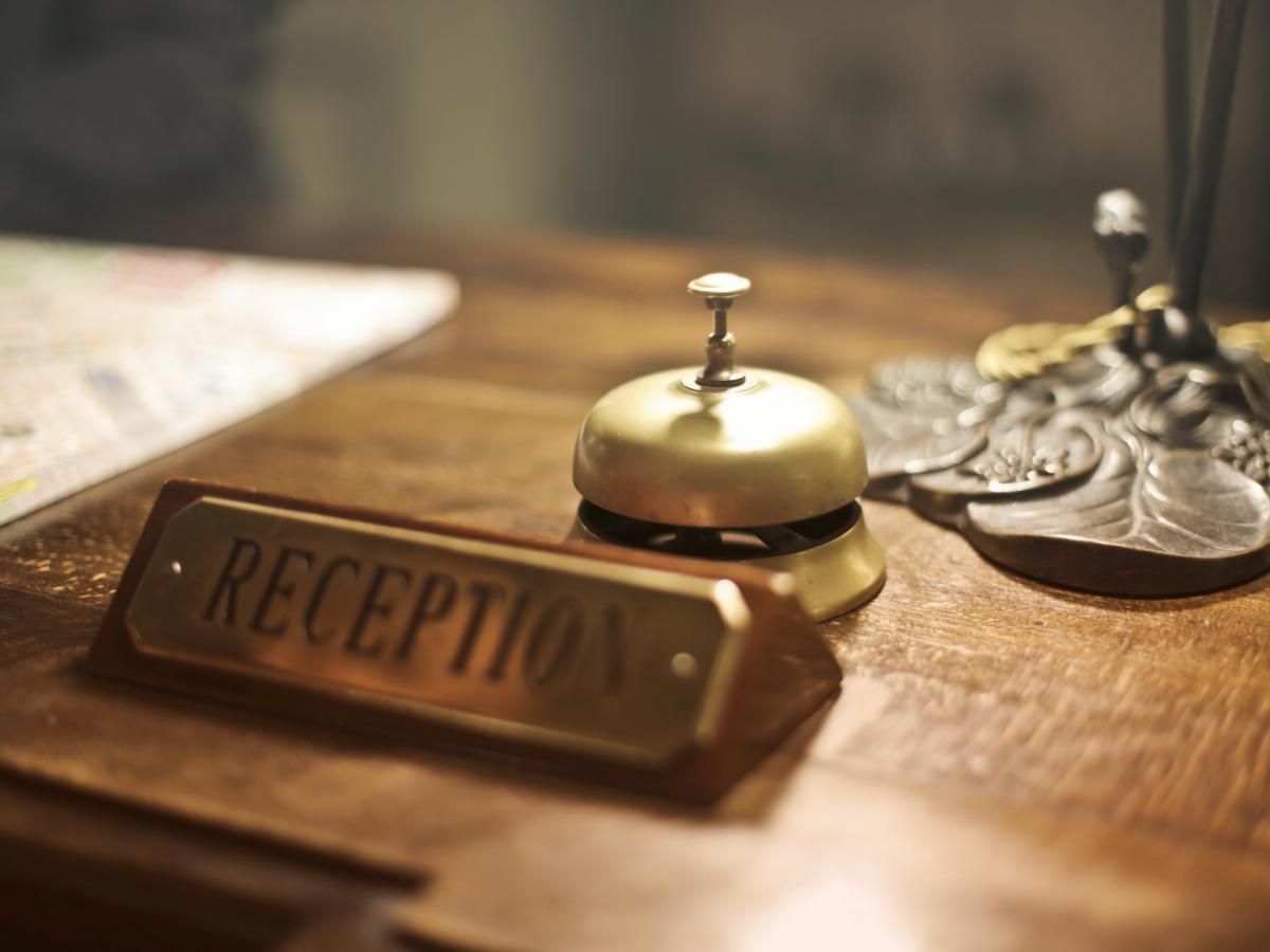 A reception bell is sitting on a wooden table next to a sign that says reception.