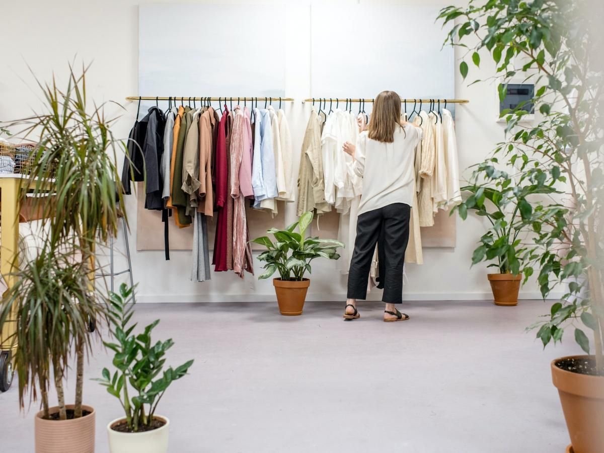 A woman is standing in front of a clothes rack in a store.