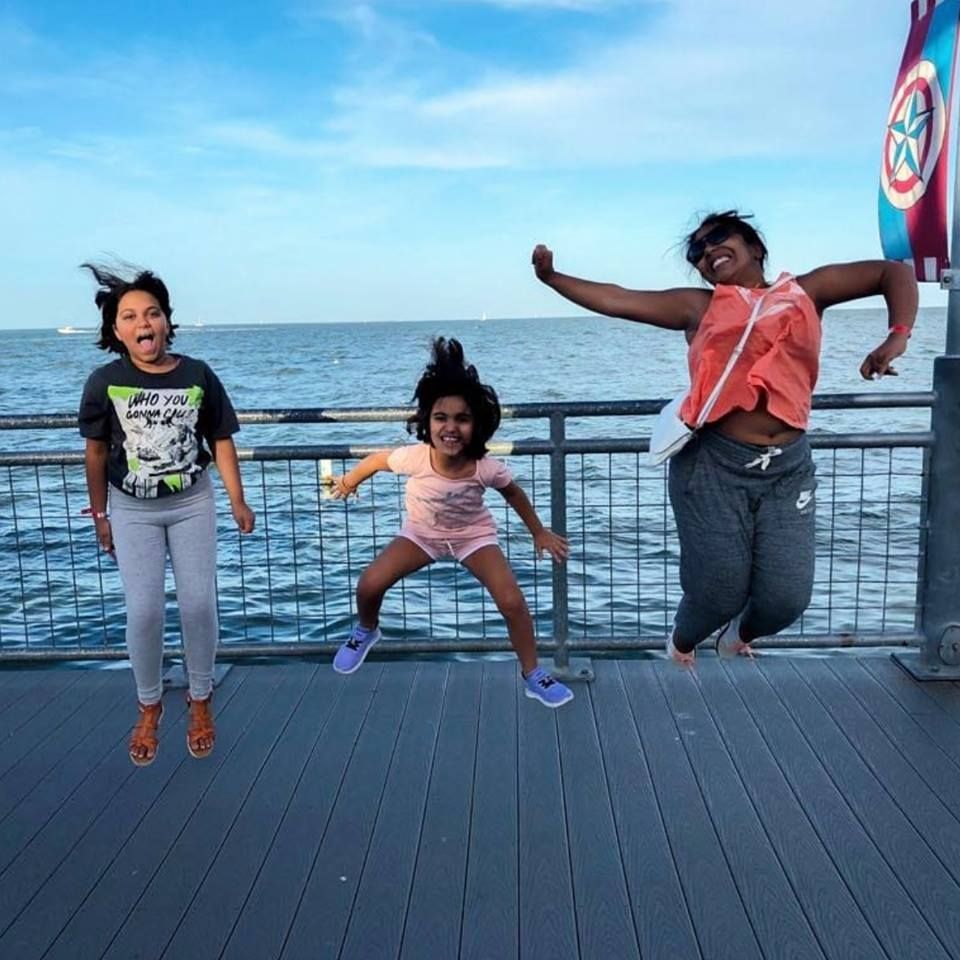 Three kids are jumping in the air by the bay