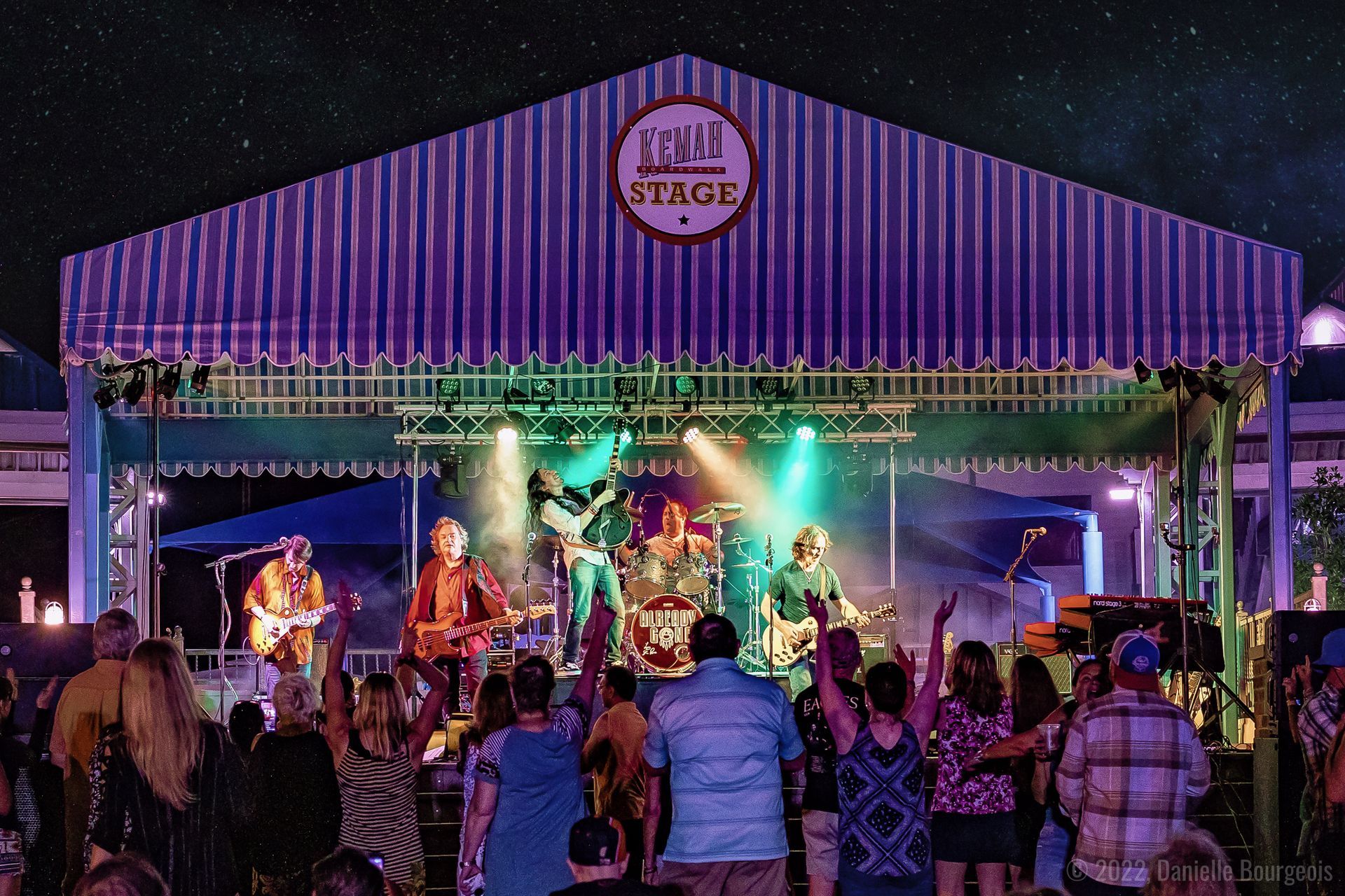 A group of people are watching a band on a stage that says local stage