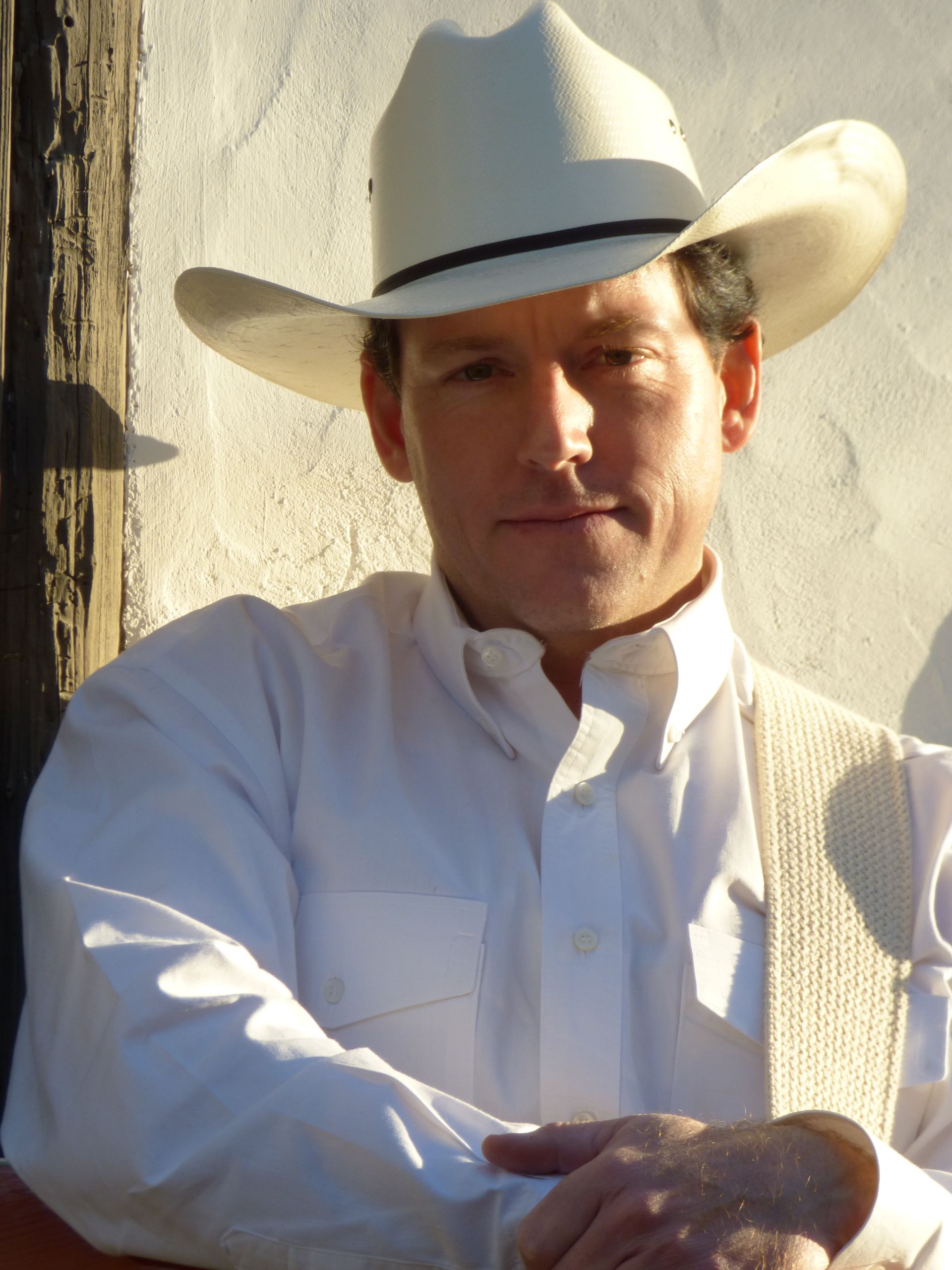 A man in a cowboy hat stands in front of a texas flag