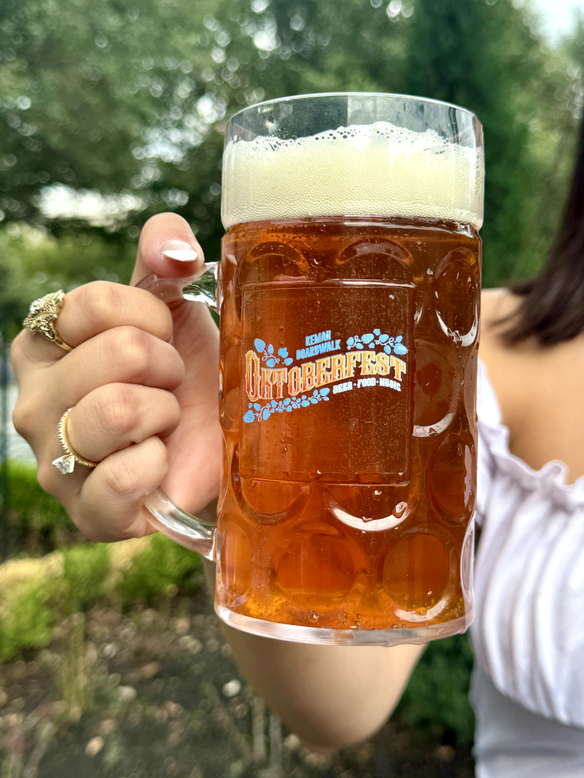 A woman is holding a beer mug that says oktoberfest on it