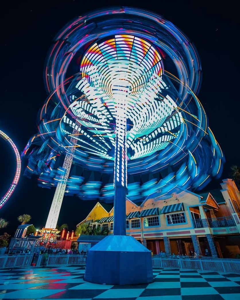A ferris wheel at an amusement park is lit up at night