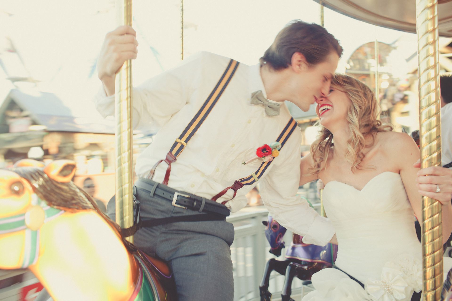 A bride and groom kissing on a merry go round