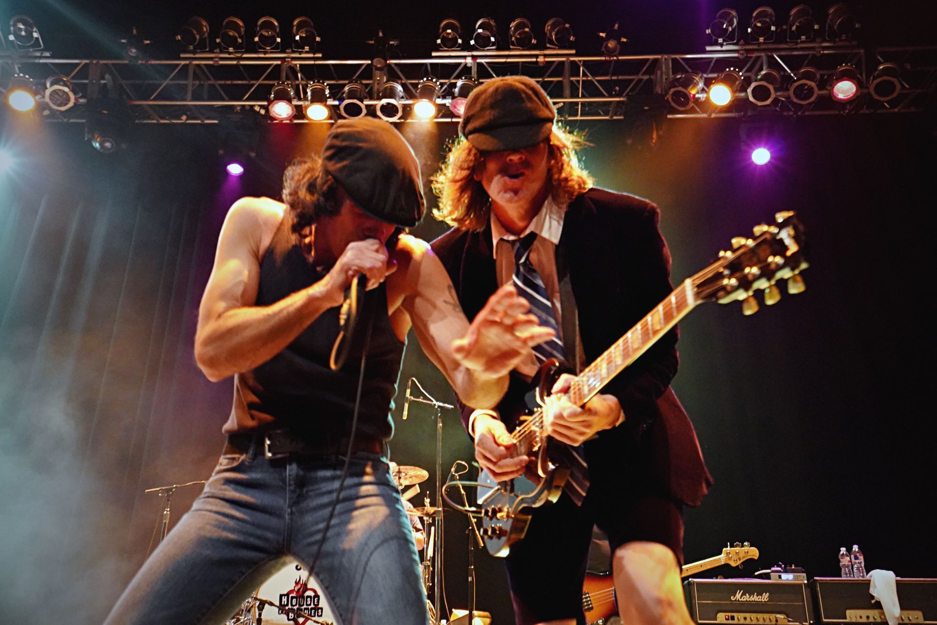 A man singing into a microphone while another man plays a guitar