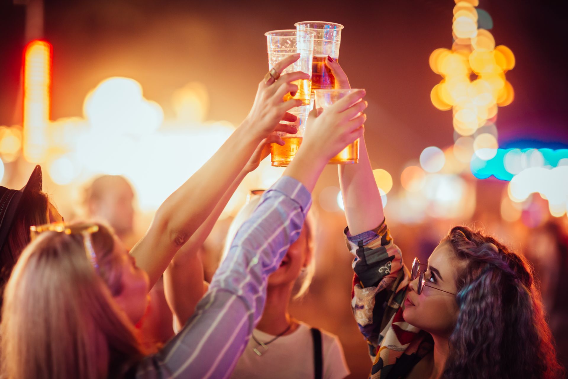 A group of women are raising their beer glasses in the air