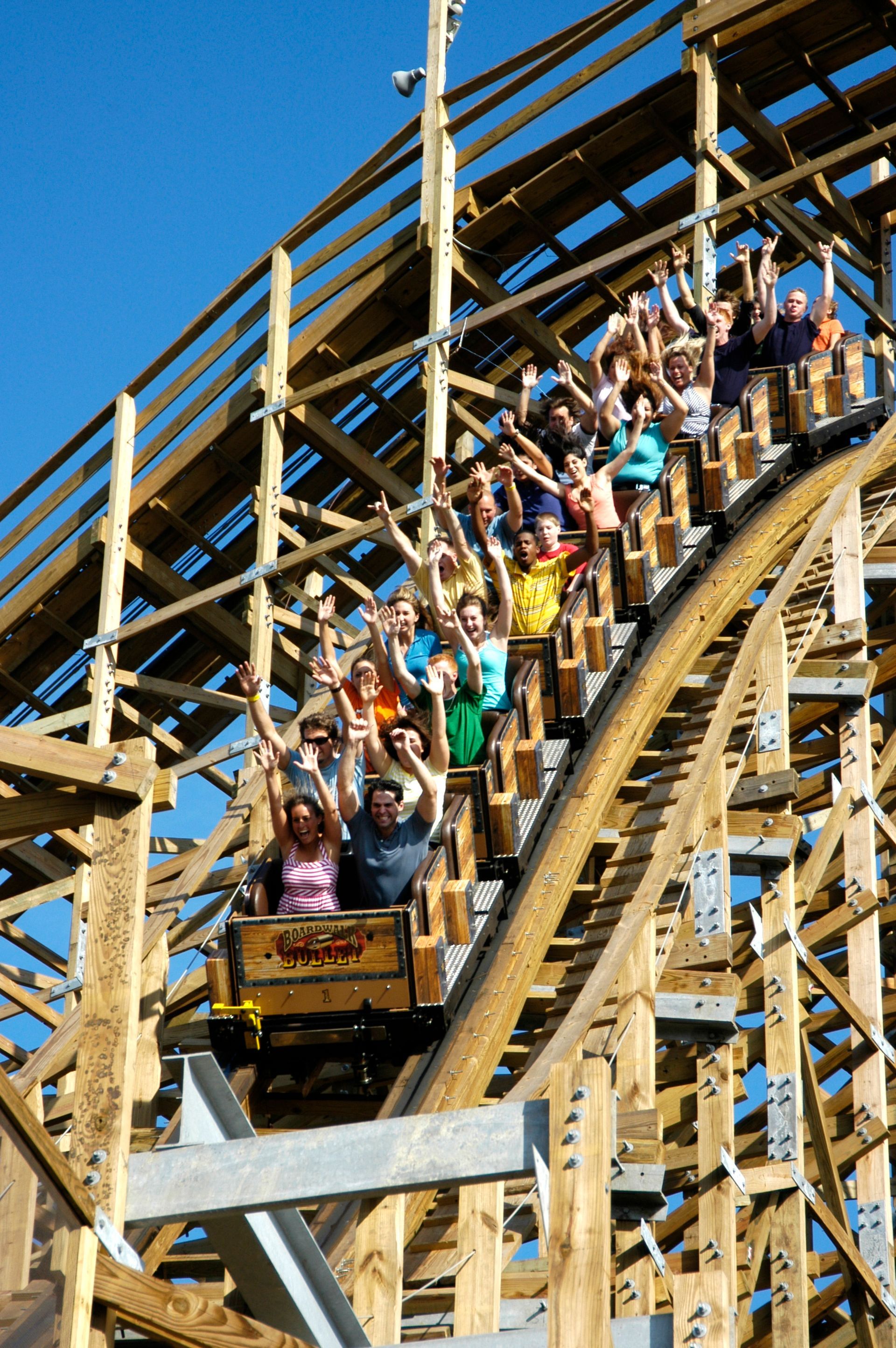 A roller coaster with people riding it with their arms in the air