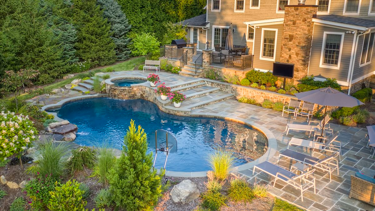 An aerial view of a large swimming pool in the backyard of a house.