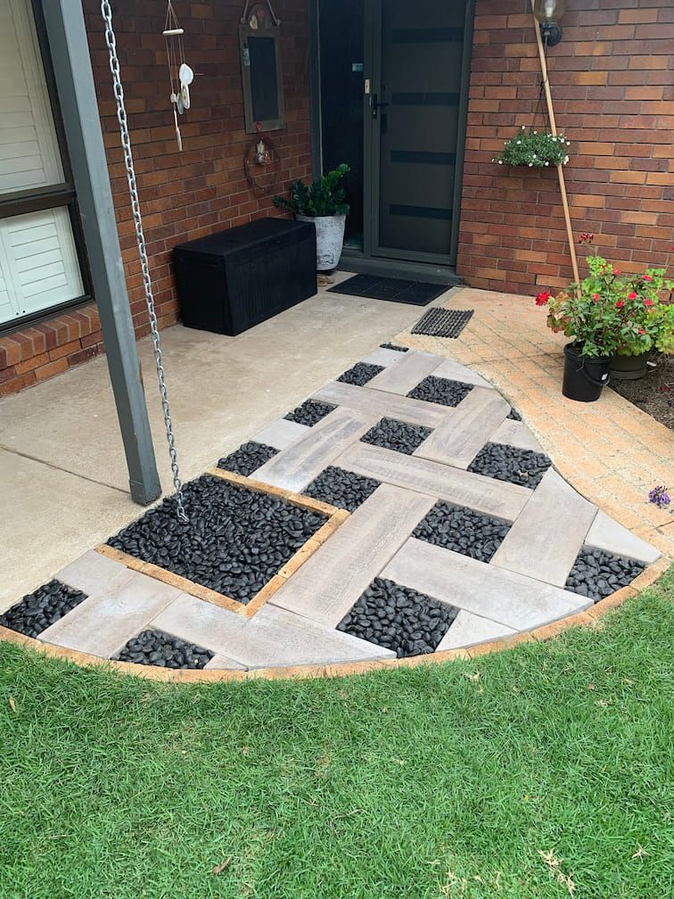 A patio with tiles and rocks in front of a brick house.