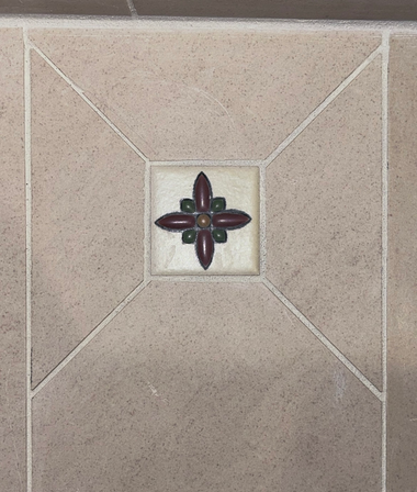Beige tiled floor with a small decorative floral tile medallion in the center