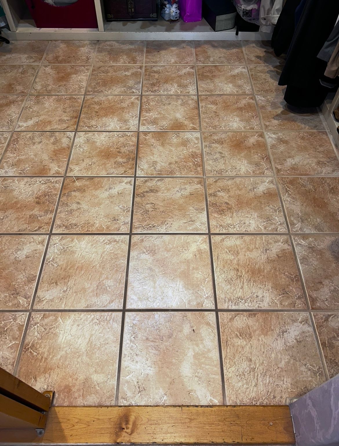 Tiled kitchen floor with tan and brown square tiles and a wooden threshold at the bottom