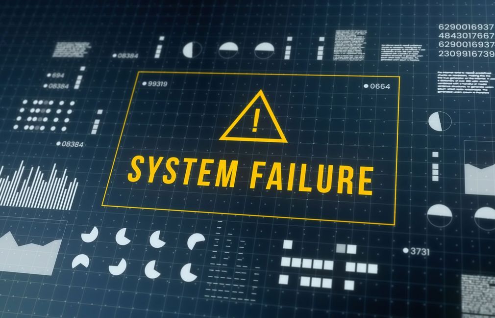Dark blue dashboard with a yellow warning triangle and “SYSTEM FAILURE” text on a screen.
