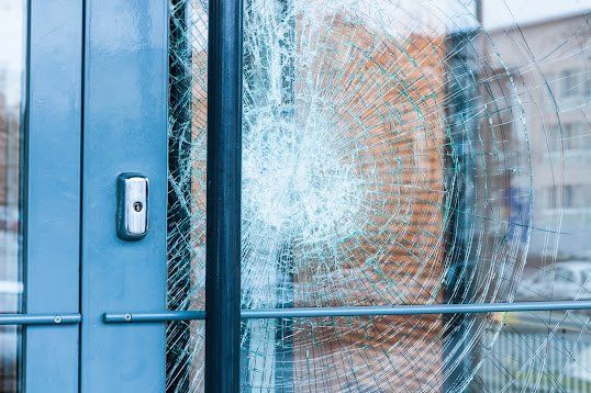 A close up of a broken glass door with a keypad.