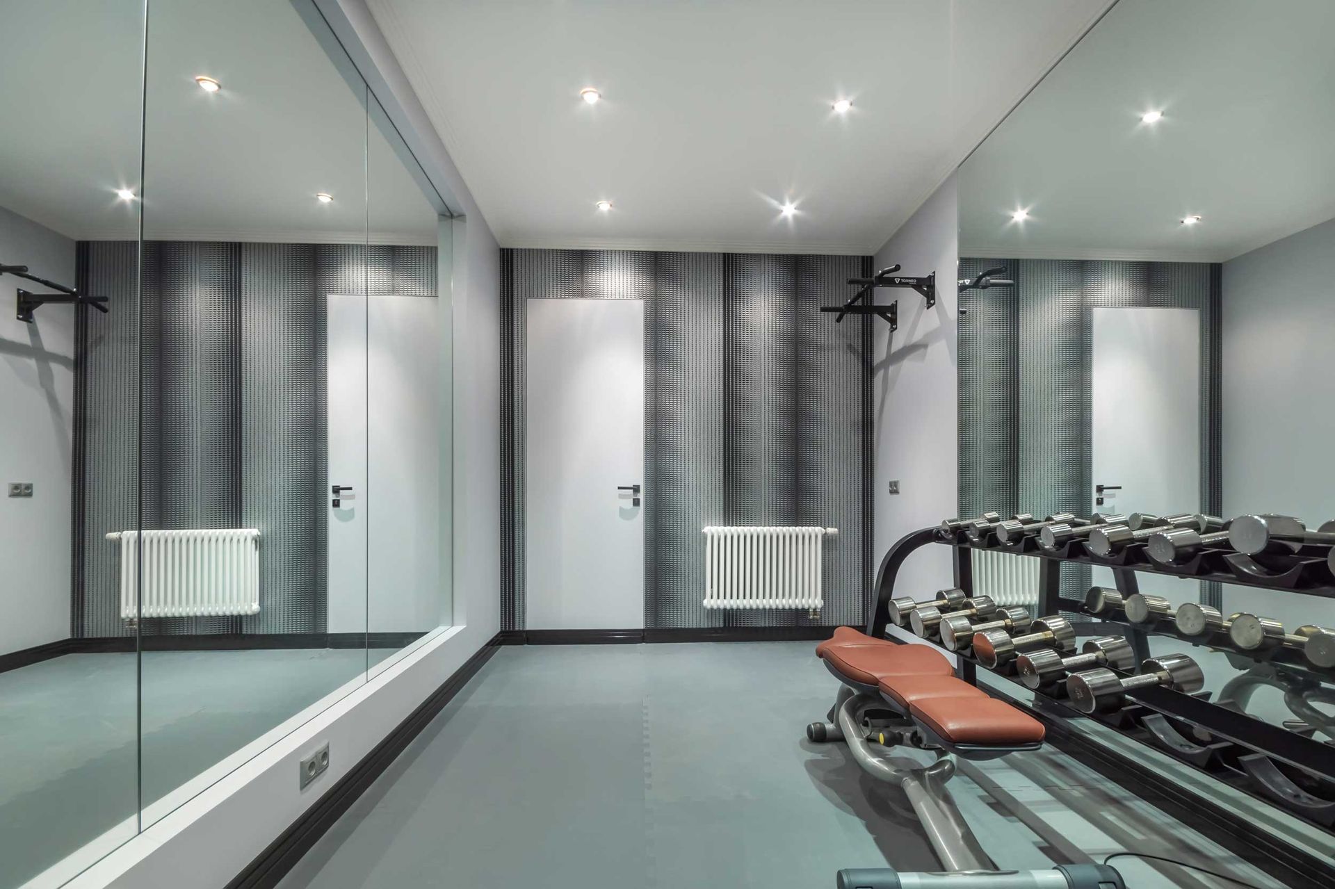 A private gym with mirrors, a rack with dumbbells and a bench for the press. A private gym with mirrors, a rack with dumbbells and a bench for the press.