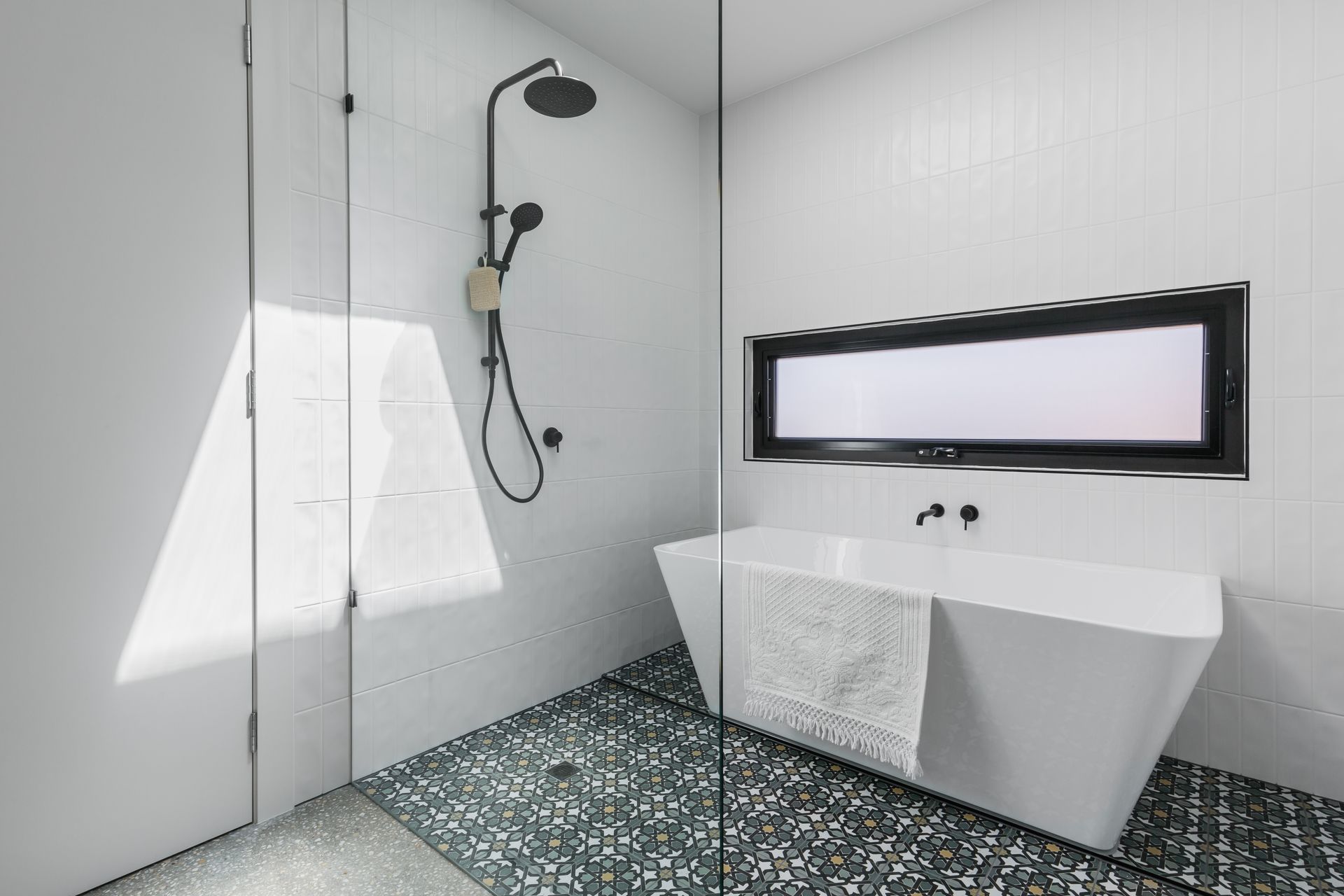A bathroom featuring a glass shower screen, sink, and bathtub, showcasing a clean and modern design.