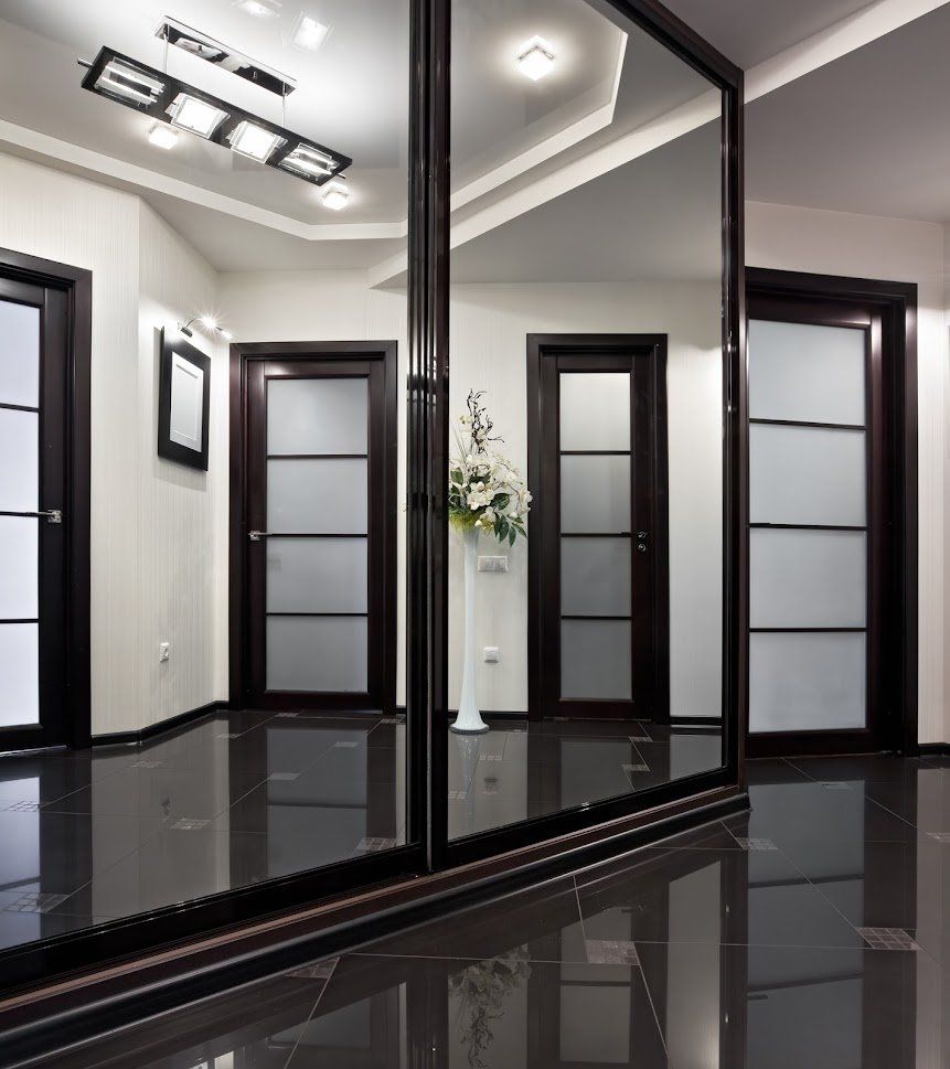 A hallway with a large mirror and a vase of flowers