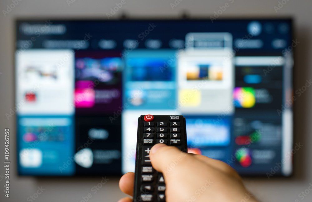 hand holding a remote control aiming at big screen TV
